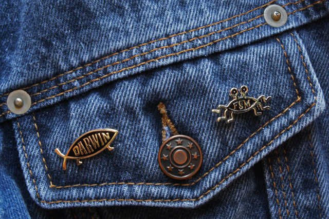 Przypinka z rybką Darwina, czyli ateistyczną przeróbką chrześcijańskiego symbolu ryby i FSM, czyli po polsku Latający Potwór Spaghetti – bóg parodystycznej religii