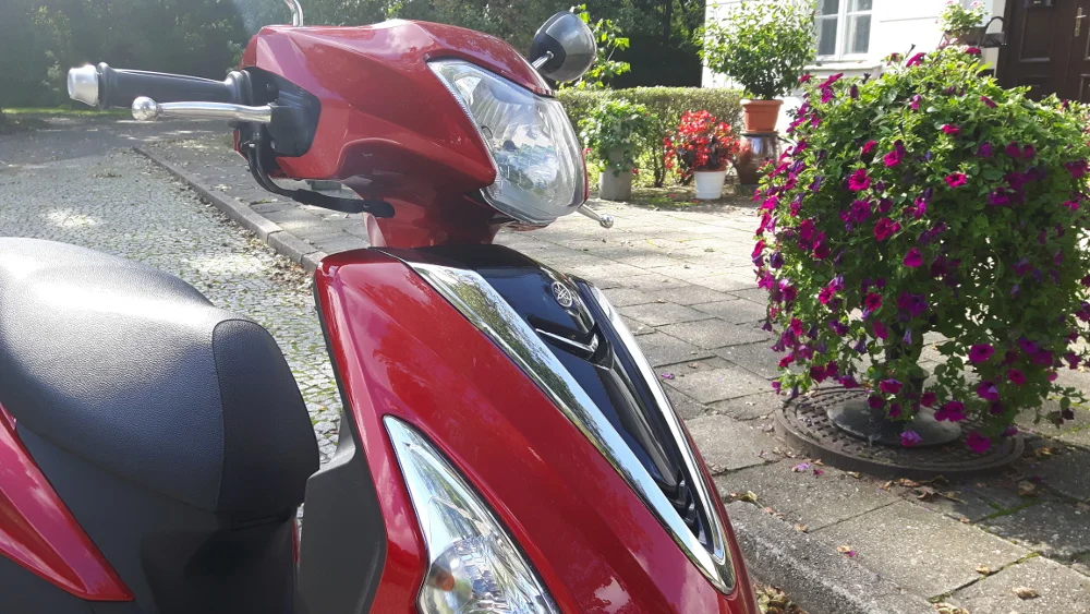 Czerwona Yamaha jest to mały, elegancki skuter.