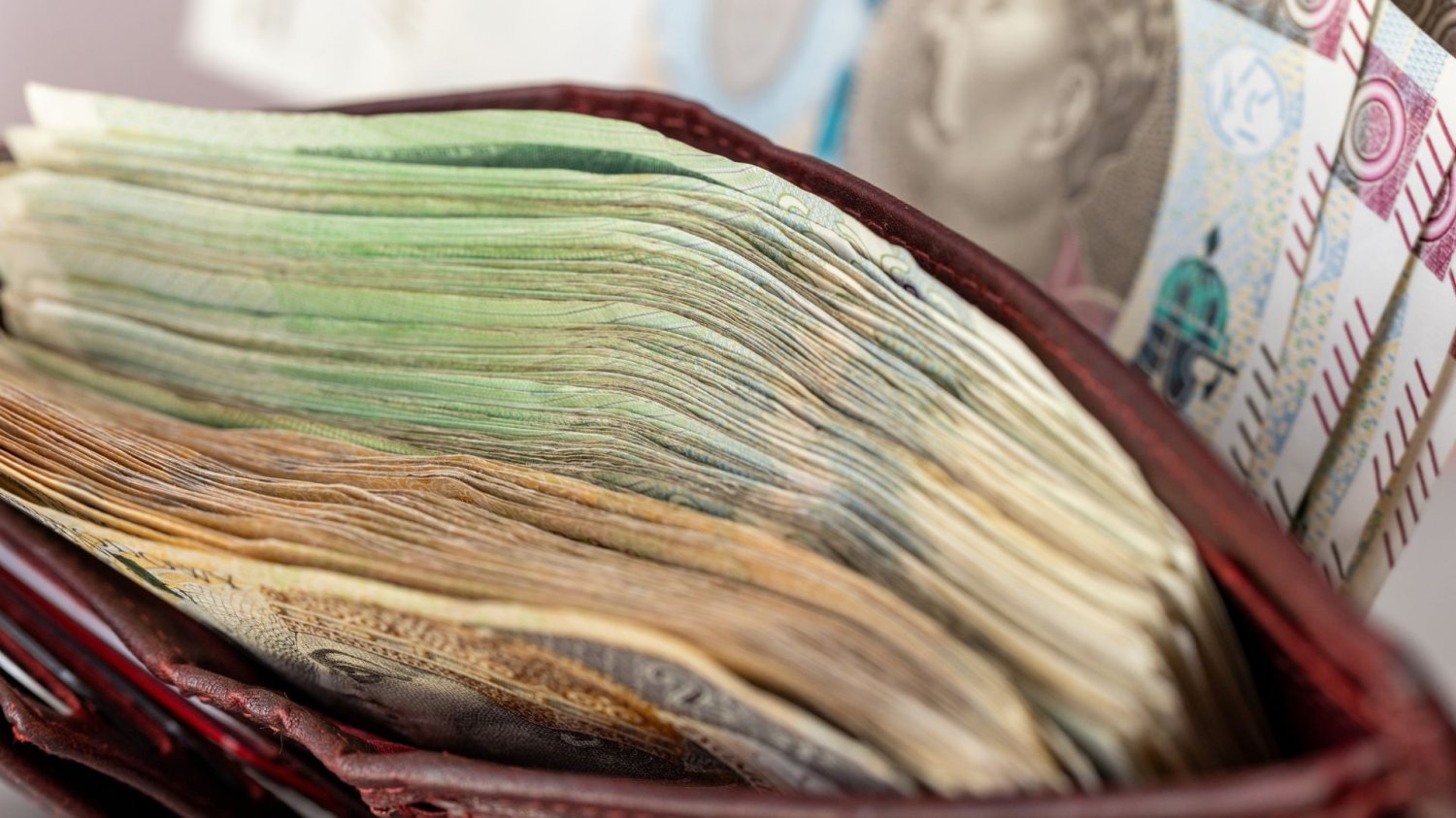 Średnie zarobki Polaków i mediana wynagrodzeń. Policzyliśmy, ile trzeba pracować, by kupić kawalerkę w Warszawie za gotówkę. Portfel pełen banknotów i banknoty 500-złotowe obok.