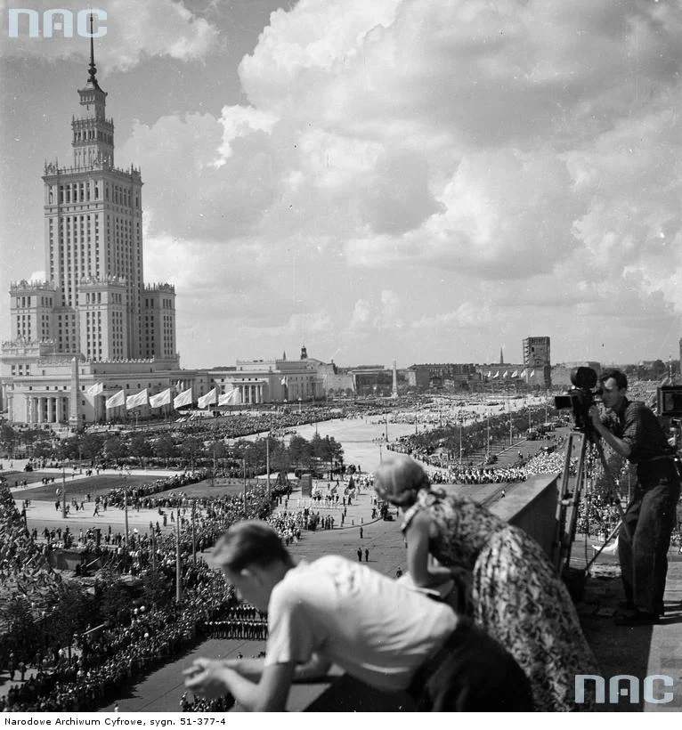 Pałac Kultury i Nauki oraz plac Defilad widoczne z dachu budynku przy ulicy Marszałkowskiej. Z prawej operator kamery filmuje pochód (1955).