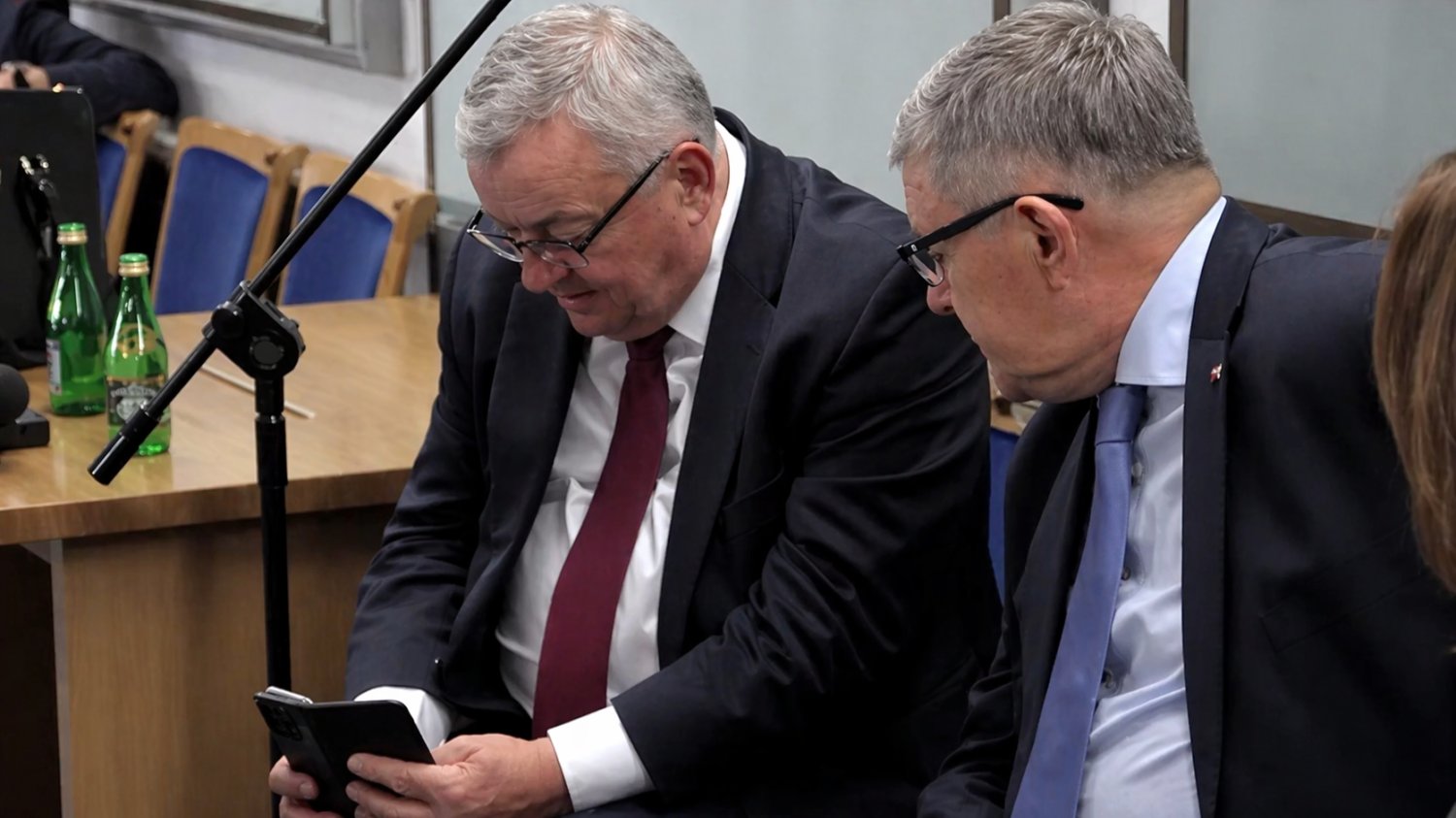 Były minister infrastruktury Andrzej Adamczyk trzyma telefon i robi zdjęcie dziennikarki w Sejmie.