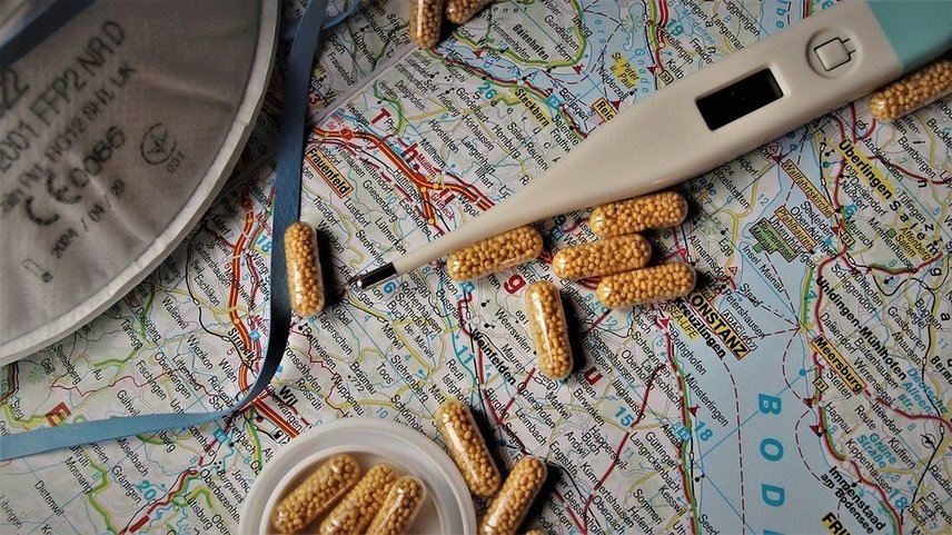Termometr, leki i maseczka higieniczna, czyli zestaw do ochrony przed koronawirusem (covid-19) na tle mapy świata.