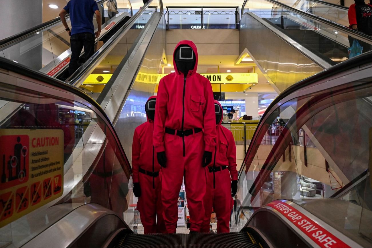 Osoby przebrane w stroje z serialu "Squid Game" w galerii handlowej.