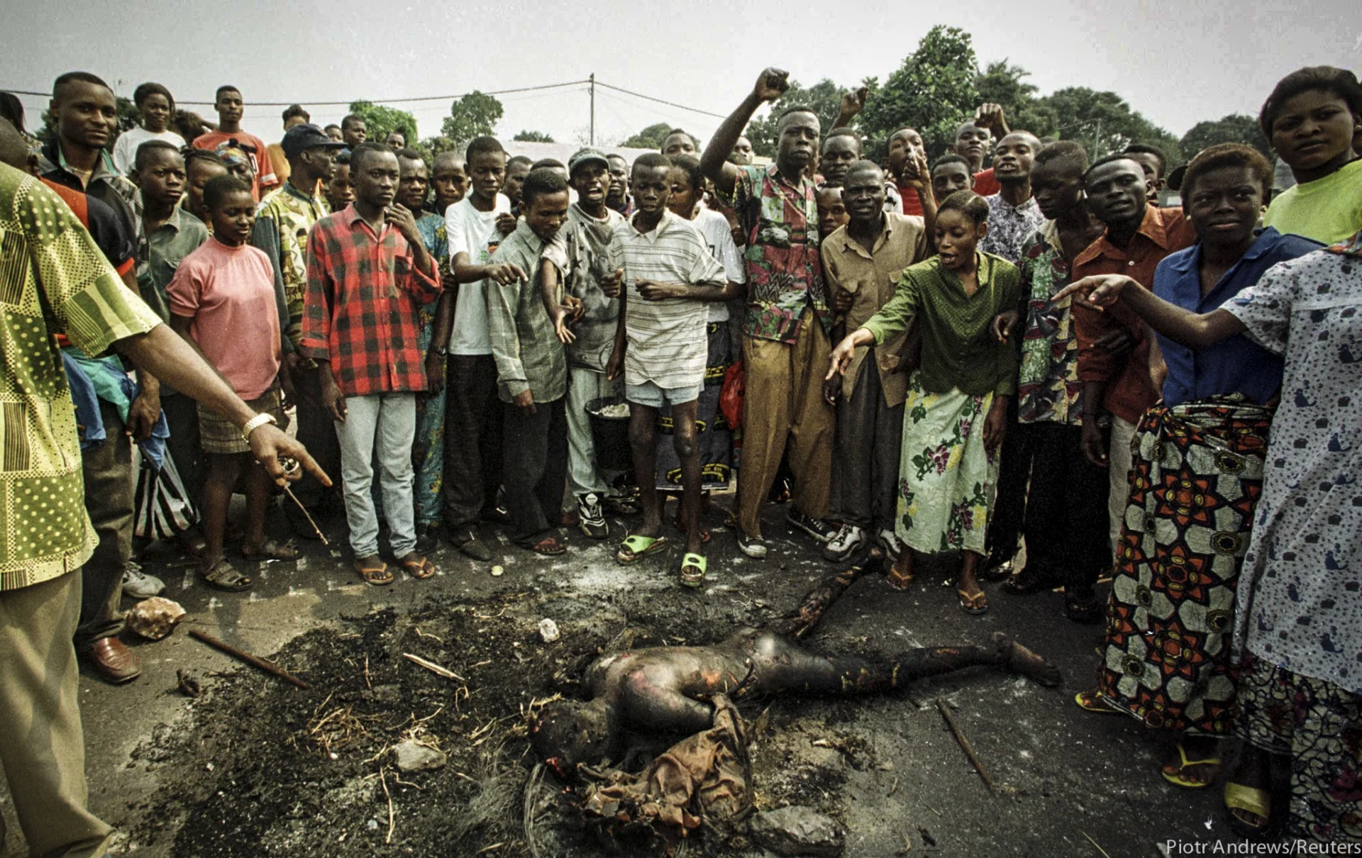 Tłum pokazuje spalone ciało mężczyzny z plemienia Tutsi