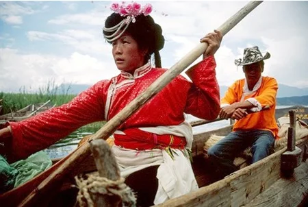 Kobieta w tradycyjnym stroju Mosuo i mężczyzna na canoe.