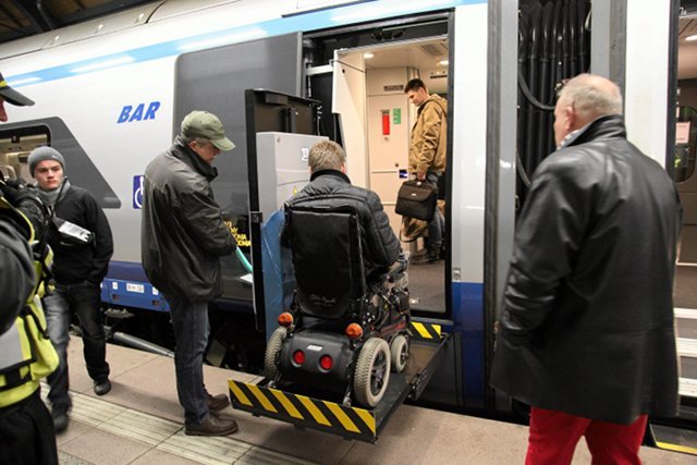 Pendolino odjeżdża z Wrocławia do Warszawy. W trzecim wagonie niepełnosprawni korzystają z windy, która pomaga im wsiąść do pociągu
