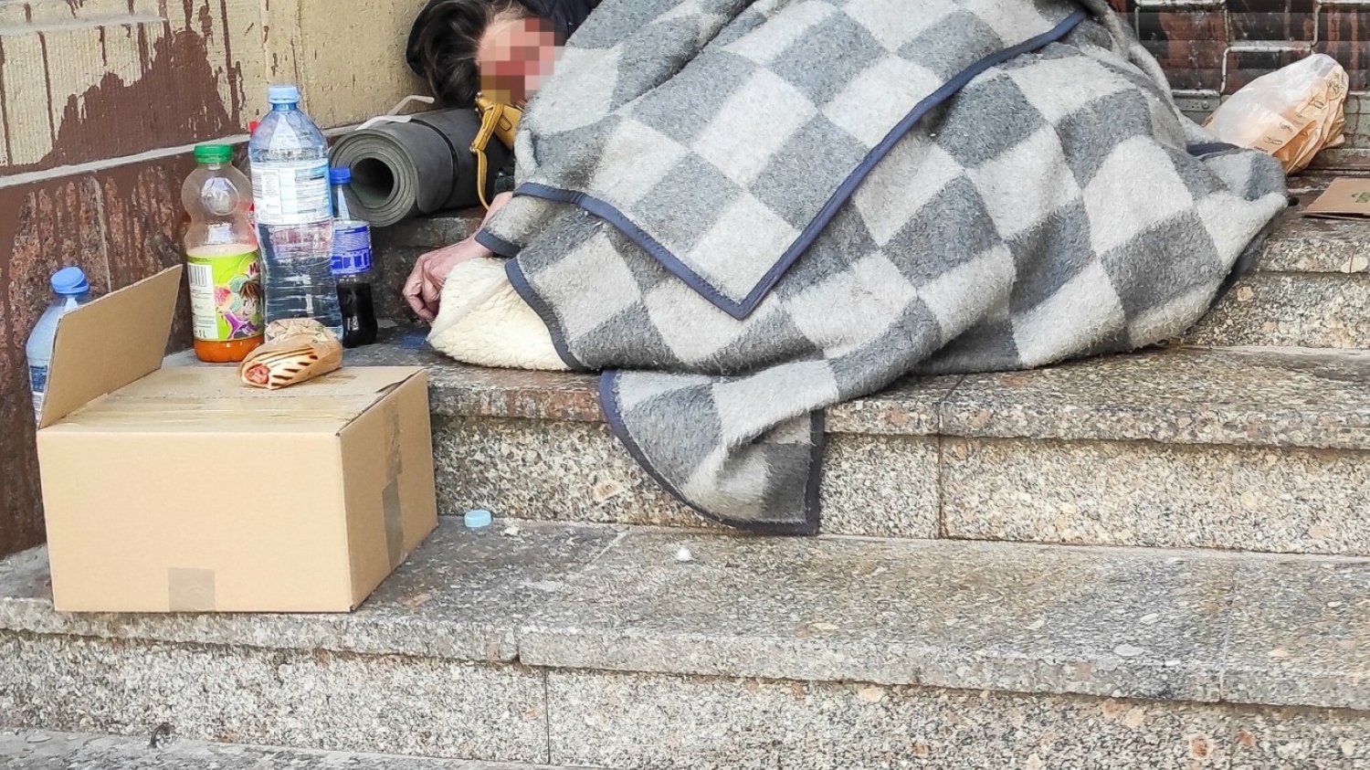 Bezdomni Polacy muszą liczyć się z deportacją z Niemiec. Bezdomna kobieta śpiąca na schodach budynku w otoczeniu swoich rzeczy.