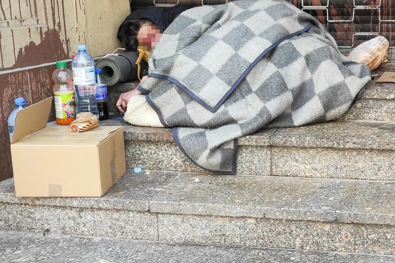 Bezdomni Polacy muszą liczyć się z deportacją z Niemiec. Bezdomna kobieta śpiąca na schodach budynku w otoczeniu swoich rzeczy.