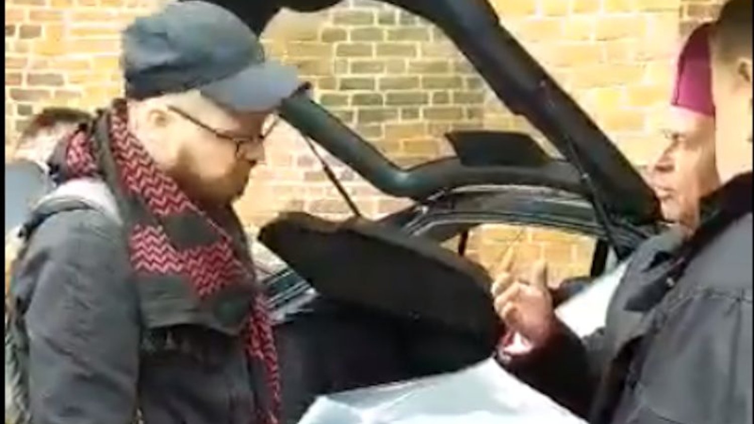 Biskup Stanisław Napierała rozmawia z dziennikarzami przed katedrą w Kaliszu.