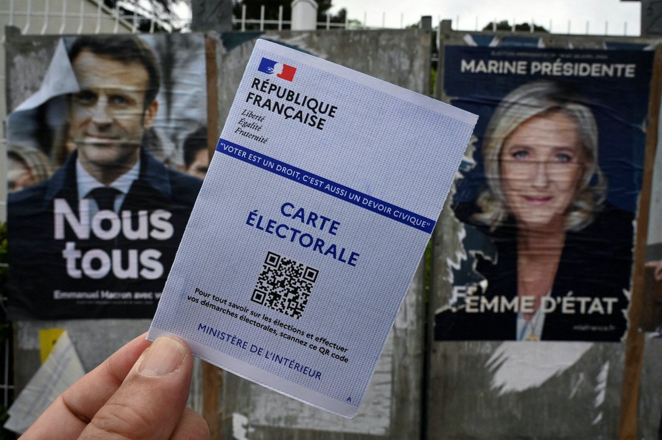 Wybory we Francji. Karta do głosowania na tle plakatów kandydatów, którzy przeszli do drugiej tury: Emmanuela Macrona i Marine Le Pen.