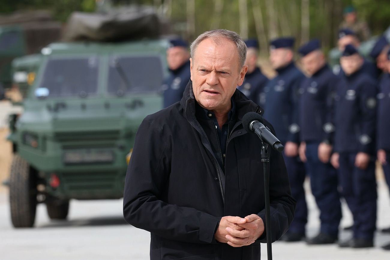 Na zdjęciu premier Donald Tusk na tle funkcjonariuszy broniących granic w czasie kryzysu migracyjnego.