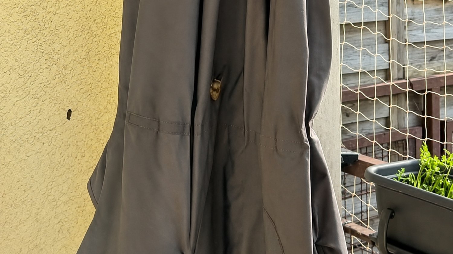 Gniazdo pszczół w parasolu na balkonie. Murarka to pożyteczny owad Złożony, ciemny parasol ogrodowy stojący na betonowym balkonie w bloku, w którego materiale ukryte jest gniazdo dzikiej pszczoły samotnicy, czyli murarki ogrodowej.