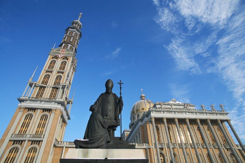 Pomnik księdza Eugeniusza Makulskiego stoi przed bazyliką w Licheniu. Ksiądz klęczy przed Janem Pawłem II.