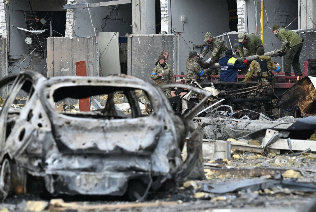 Ukraińscy funkcjonariusze ładują fragment rakiety na ciężarówkę przed budynkiem w Kijowie