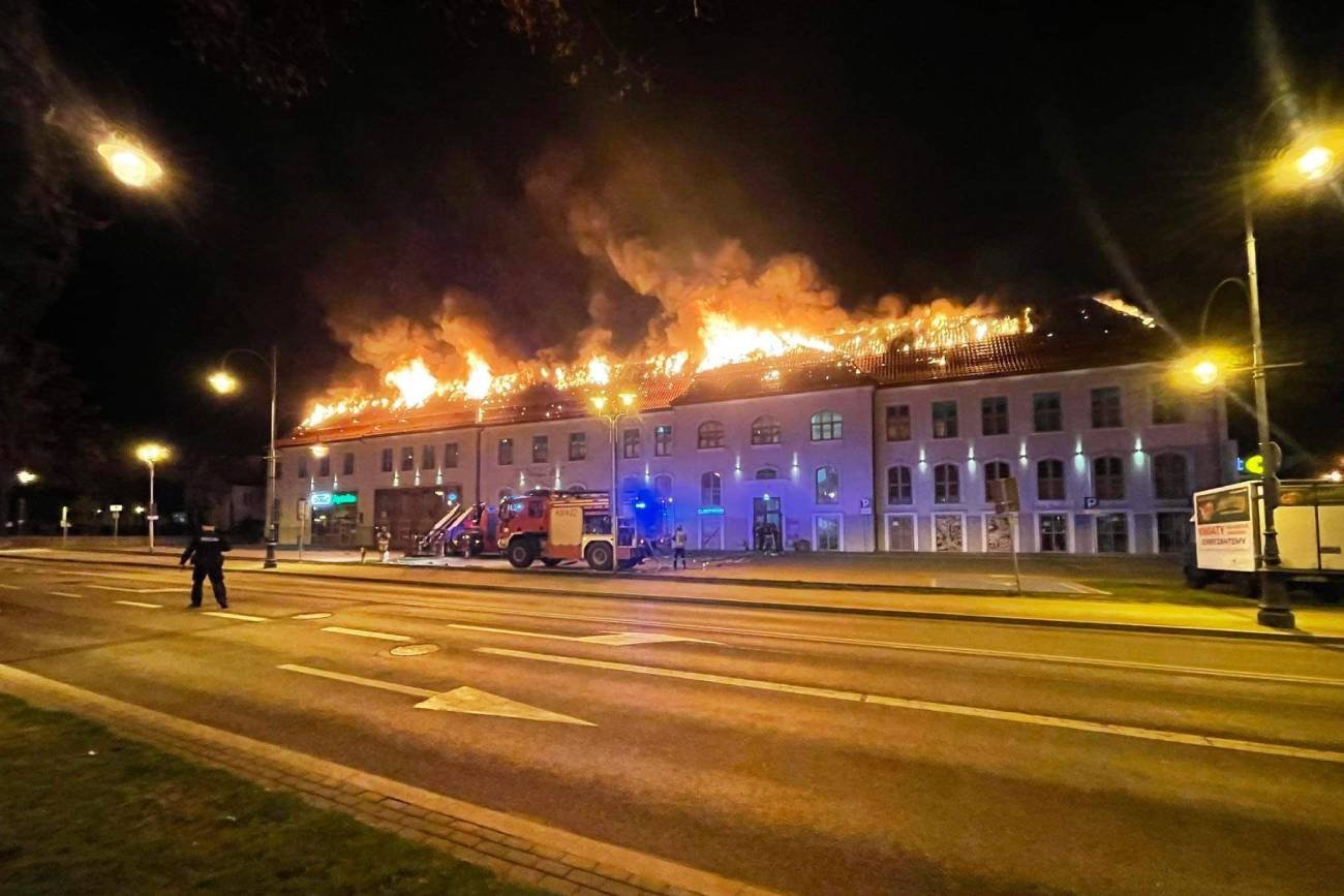 Strażacy przed budynkiem, w którym płonie dach