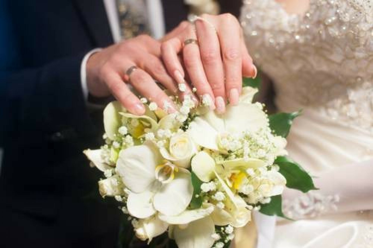 Ręce państwa młodych nad bukietem