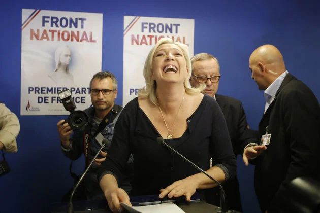 Marine Le Pen na tle plakatów "Front Narodowy - pierwszą partią Francji"