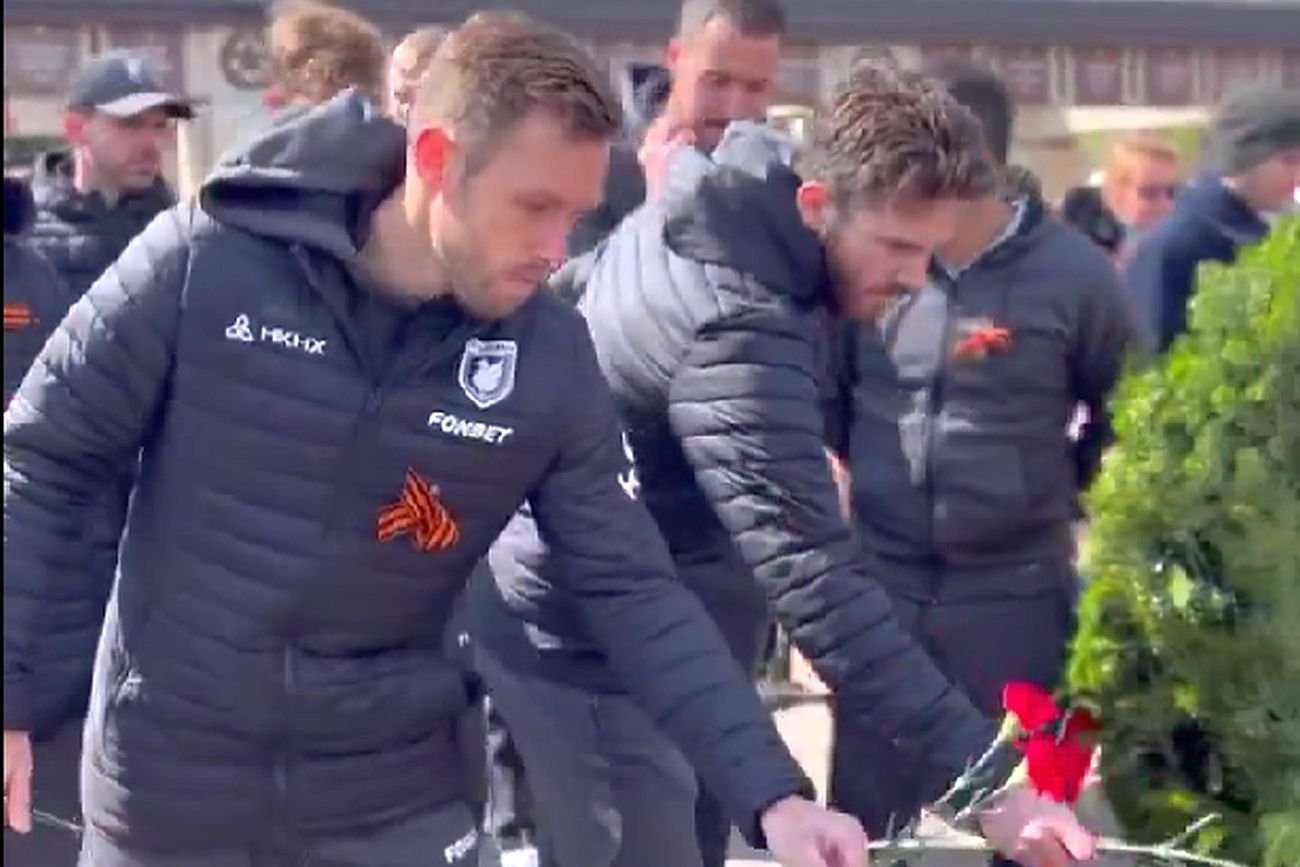 Maciej Rybus z koloradą na kurtce składa kwiaty w rosyjski Dzień Zwycięstwa