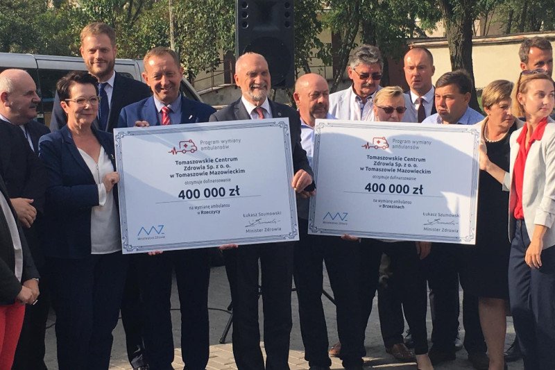 Antoni Macierewicz trzyma czek, a wiceminister zdrowia stoi w drugim rzędzie.