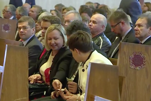 Urszula Gacek w trakcie mszy podaje banknot Beacie Szydło.