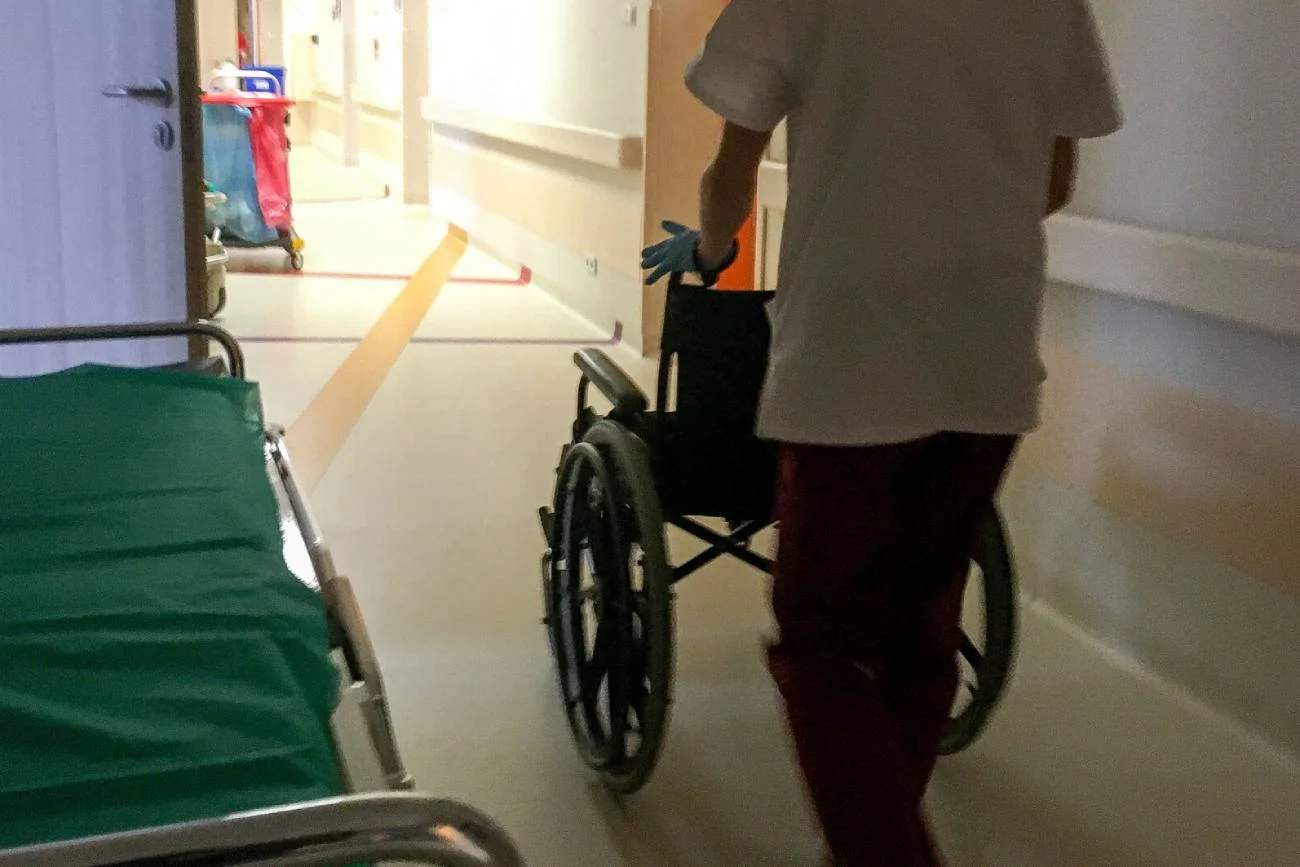 pracownik medyczny prowadzi wózek inwalidzki