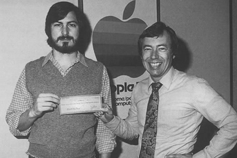Mike Markkula przekazuje Steve'owi Jobsowi czek na 250 tysięcy dolarów dzięki czemu udało się rozwinąć firmę.