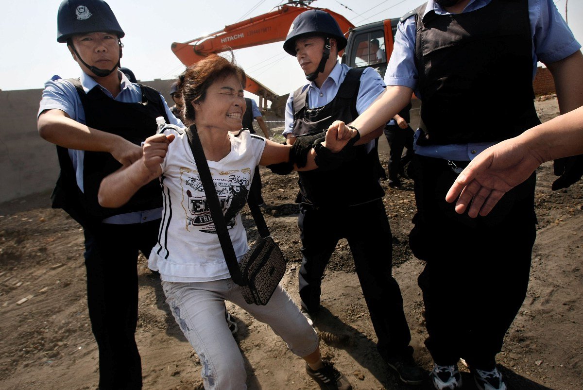 Policja aresztuje kobietę, która próbuje przeszkodzić rozbiórce "nielegalnego" budynku w dzielnicy Kuancheng w mieście Changchun, w prowincji Jilin. 9 czerwca 2010. Fang Xinwu/Color China Photo/AP Photo