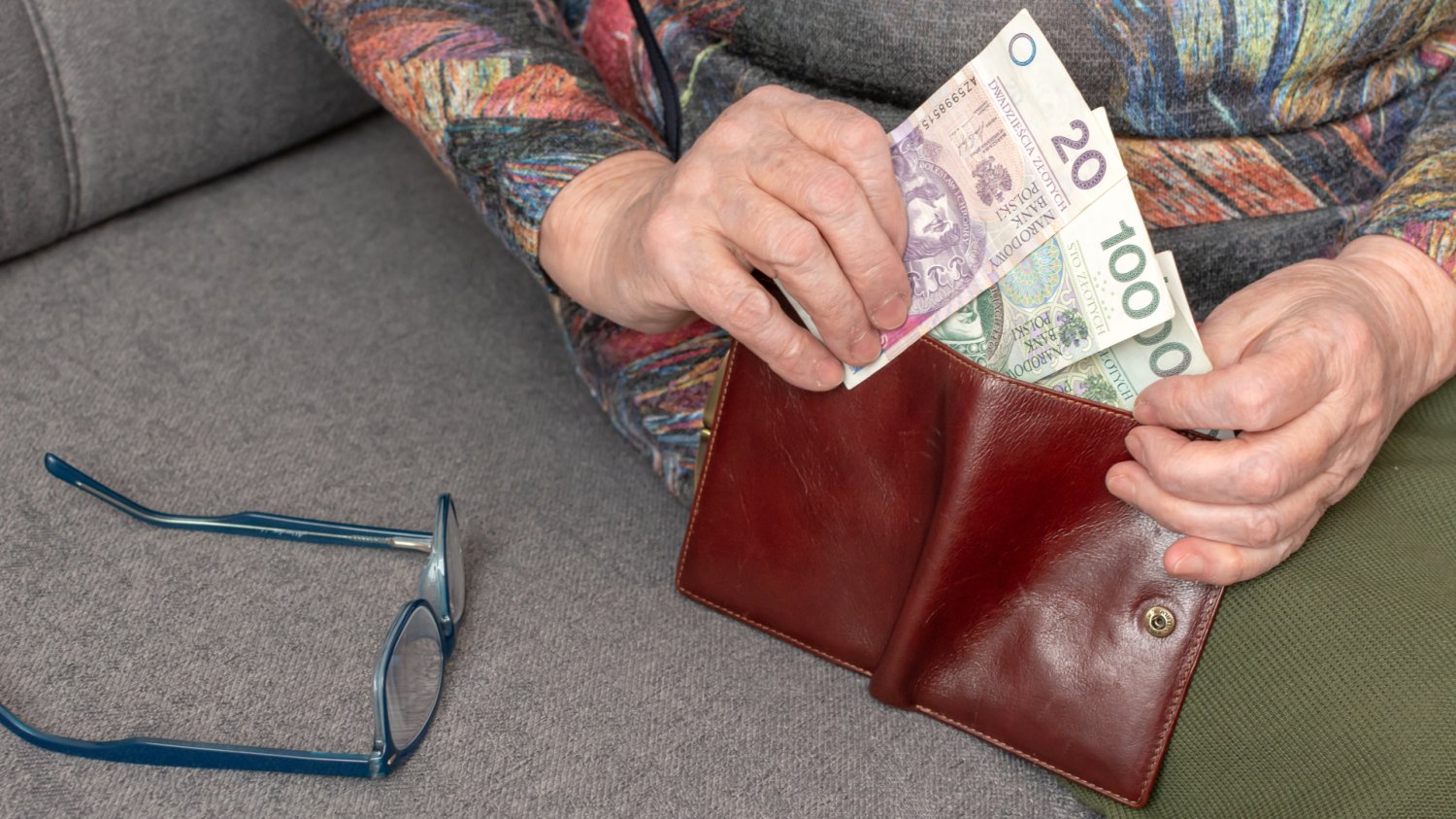 Waloryzacja emerytur 2027 i prognozy podwyżek Starsza osoba wyciąga banknoty z portfela, co symbolizuje niską waloryzację emerytur w 2027 roku w stosunku do kosztów życia.