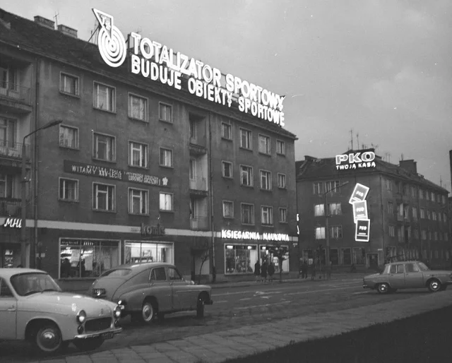 Na kamienicach neony reklamujące Totalizator Sportowy i PKO. Widoczne także samochody - od lewej: Syrena 104 i FSO Warszawa.