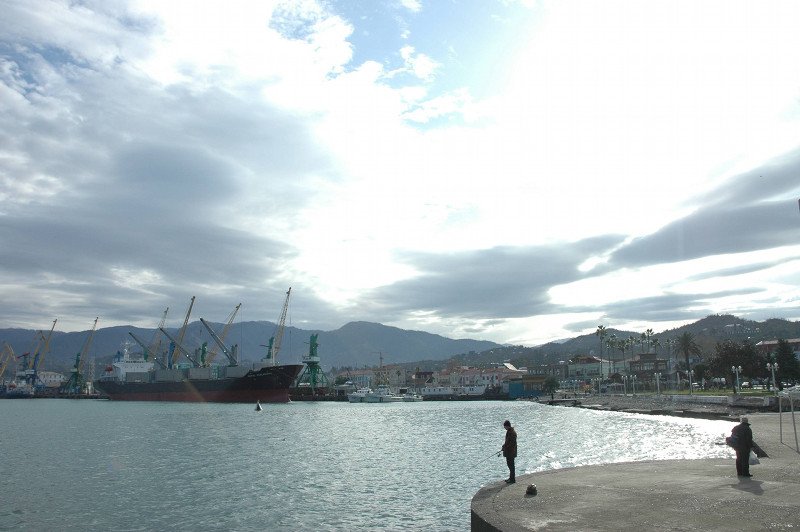 Port w Batumi nad Morzem Czarnym. W niedalekiej odległości od niego znajduje się też plaża, przy której można przespacerować się zielonym bulwarem i kupić orzeszki oraz piwo.