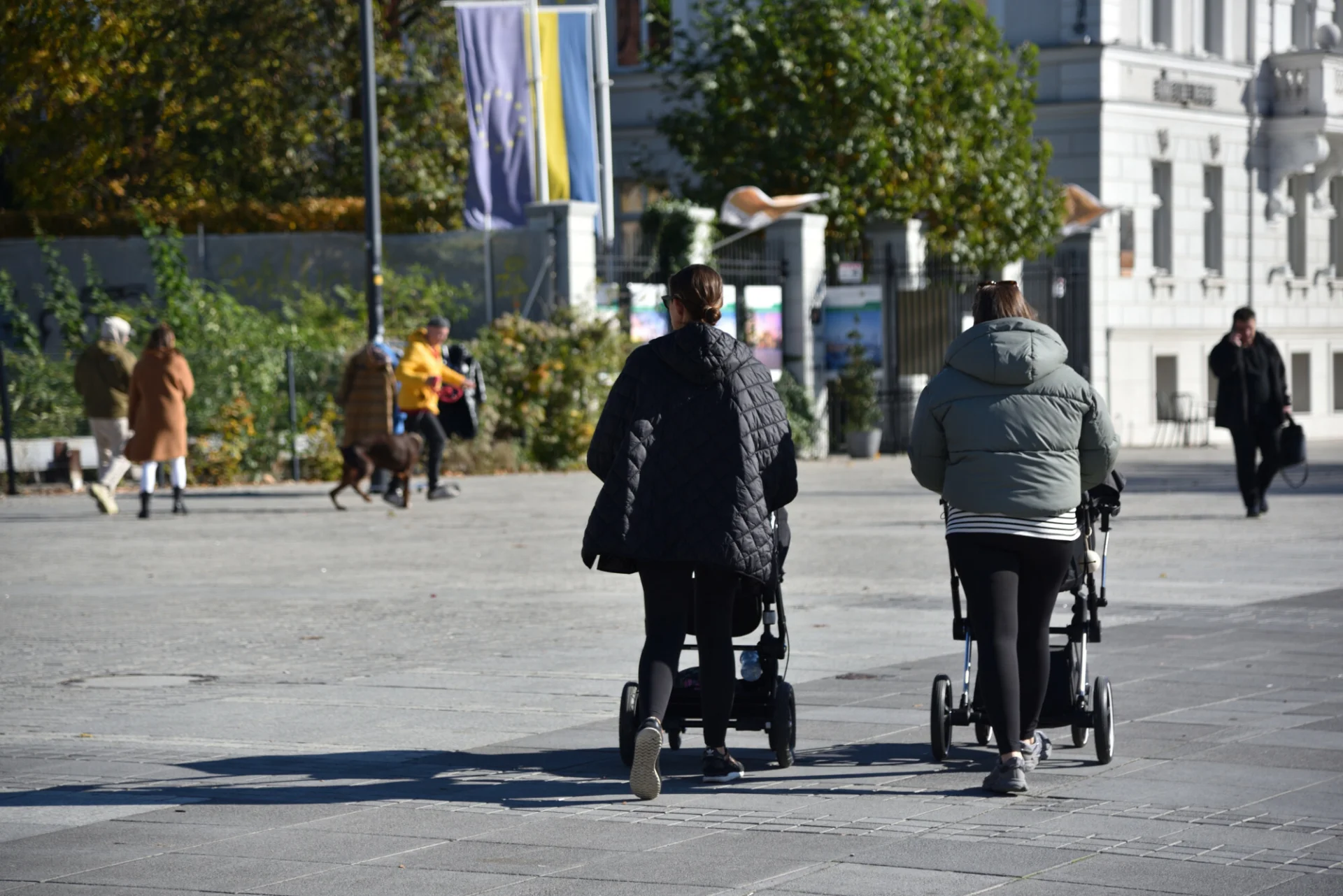 Prognozy pogody na wrzesień 2024. Jaki będzie początek jesieni w tym roku? Jesień w Europie Środkowej. Na zdjęciu widoczne dwie kobiety z wózkami dziecięcymi na ulicy obsypanej już spadającymi liśćmi.