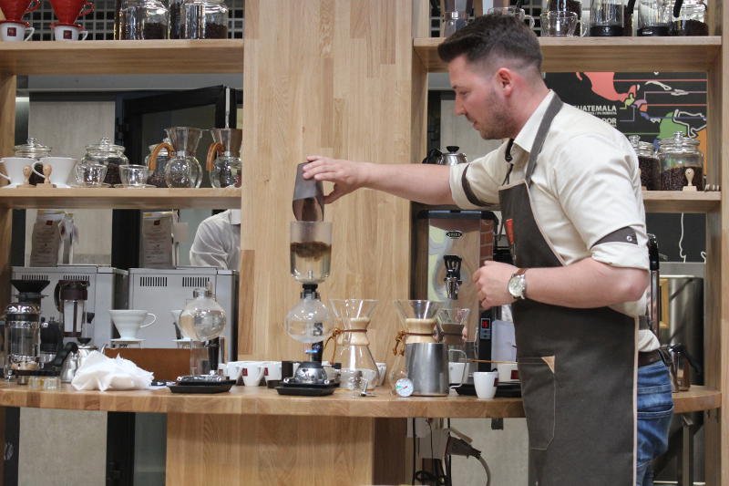 Barista Łukasz Mitura przygotowuje świeżo paloną kawę w syphonie.