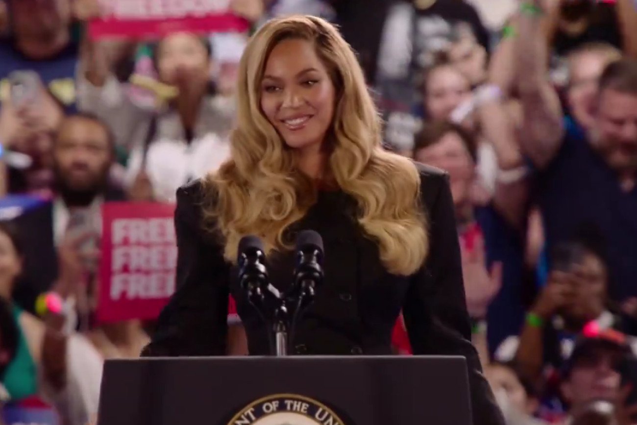 Beyoncé na scenie podczas wiecu wyborczego w Houston. W tle publiczność i transparenty popierające Kamalę Harris.