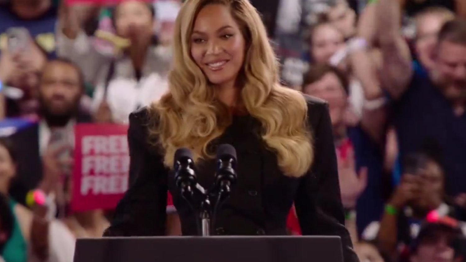 Beyoncé na scenie podczas wiecu wyborczego w Houston. W tle publiczność i transparenty popierające Kamalę Harris.