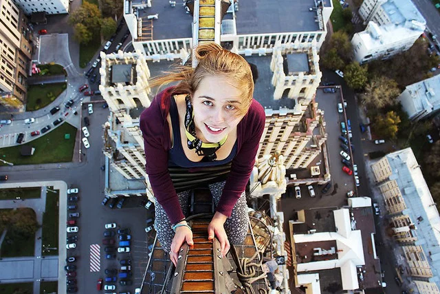 Angela  Nikolau robi selfie znad krawędzi drapaczy chmur.