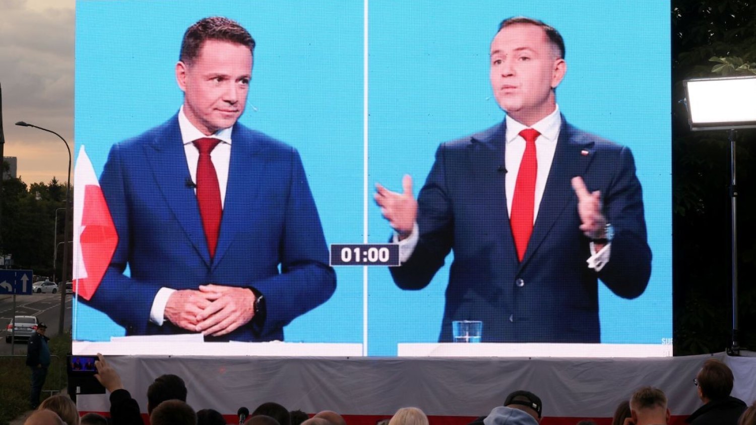 Rafał Trzaskowski i Karol Nawrocki na telebimie pokazujacym debatę prezydencką.