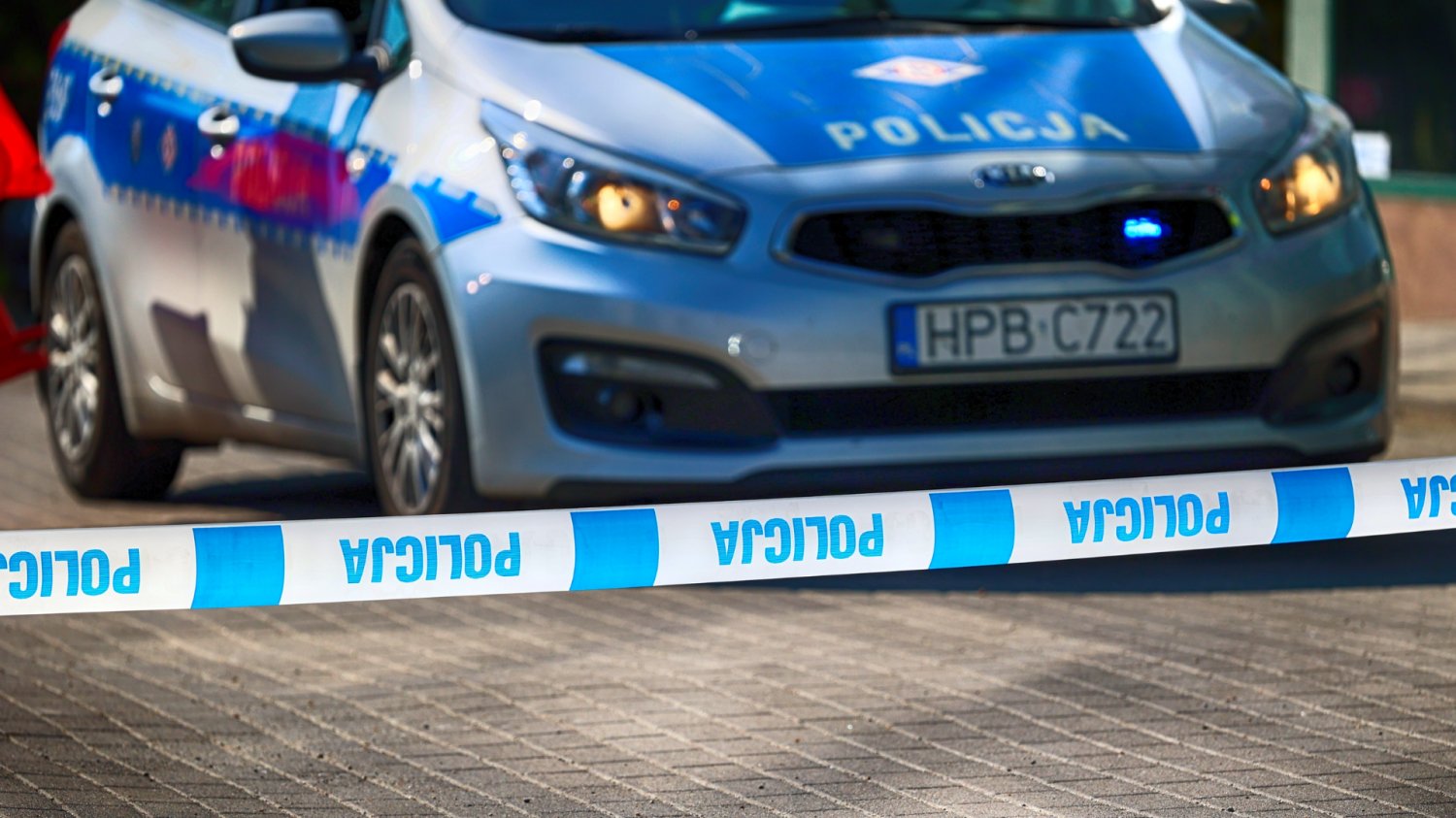 Samochód policji i taśma ostrzegawcza.