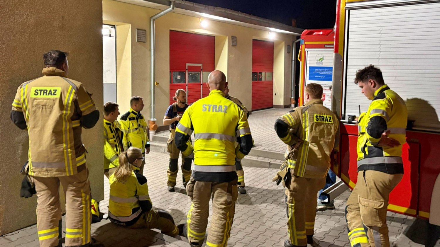Zdjęcie symbol po tragedii w Łomiankach. Strażacy wokół wozu strażackiego