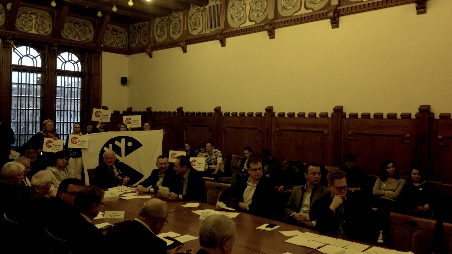 Działacze krakowskiej Inicjatywy Przeciwko Igrzyskom przez całe obrady Rady Miejskiej trzymali transparent z logiem - znacznie lepszym niż parzenica z kwadratem.