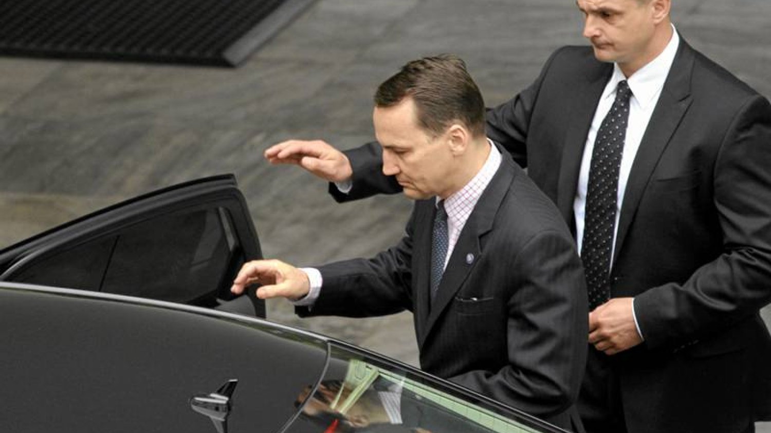 Radosław Sikorski wsiadający do służbowego samochodu.