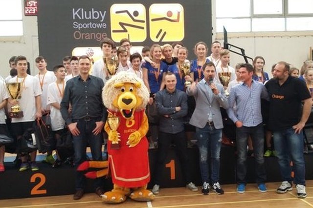 Zwycięzcy finału Pucharu Orange na podium wraz z maskotką jednej z drużyn, gospodarzem spotkania i ambasadorami programu