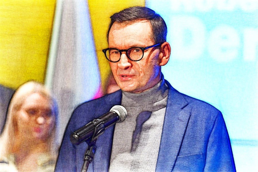 Mateusz Morawiecki stojący przy mikrofonie podczas konferencji prasowej.