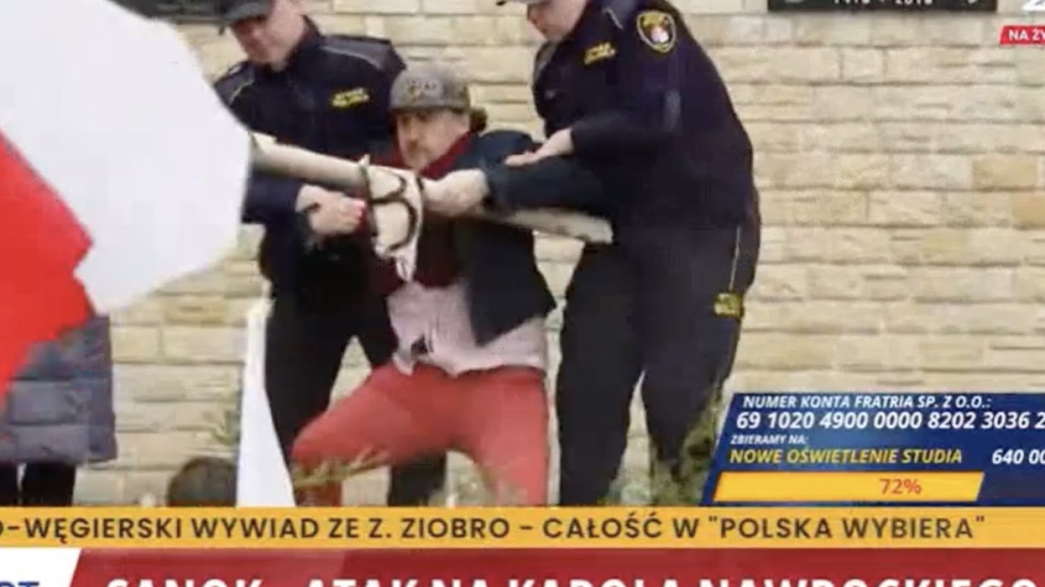 Incydent na spotkaniu Karola Nawrockiego w Sanoku. Interweniowała policja. Strażnicy miejscy wyrywają mężczyźnie transparent dotyczący fałszywej tożsamości Karola Nawrockiego, której używał, by chwalić samego siebie.