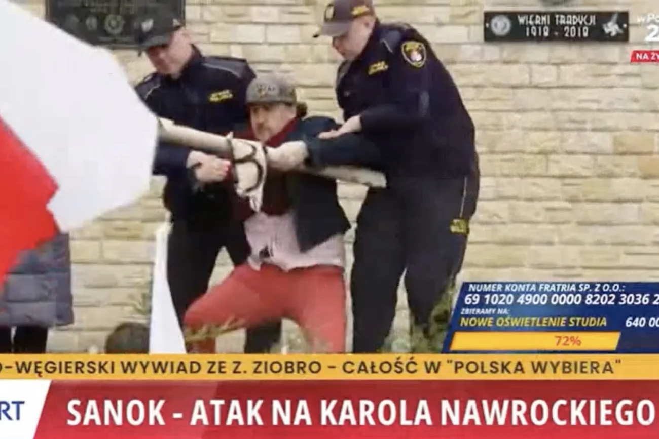 Strażnicy miejscy wyrywają mężczyźnie transparent dotyczący fałszywej tożsamości Karola Nawrockiego, której używał, by chwalić samego siebie.