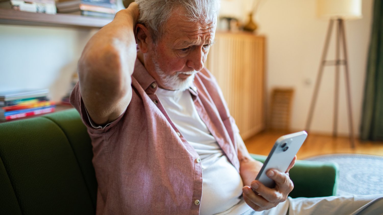 Oszustwo na pracownika ZUS i fałszywe SMS-y 2026 Zmartwiony starszy mężczyzna z telefonem. Oszuści podszywają się pod ZUS, obiecując wyższą emeryturę przez fałszywe SMS-y.