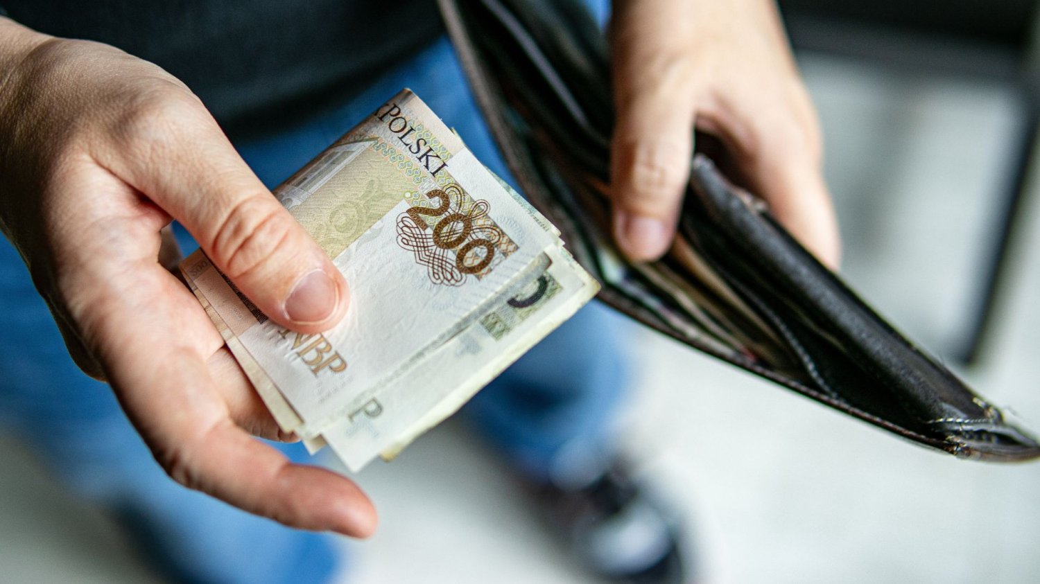 Polacy masowo składają wnioski do ZUS. Sprawdź, czy też możesz dostać pieniądze Osoba chowająca banknoty do portfela.