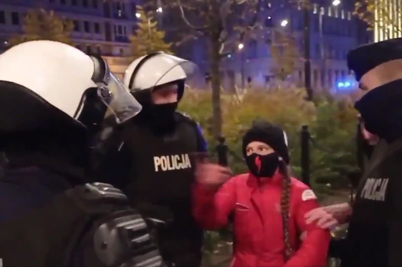 Kobietę niosło do radiowozu trzech policjantów.