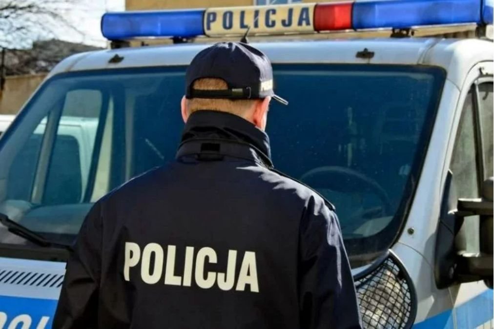 Policjant obok radiowozu.