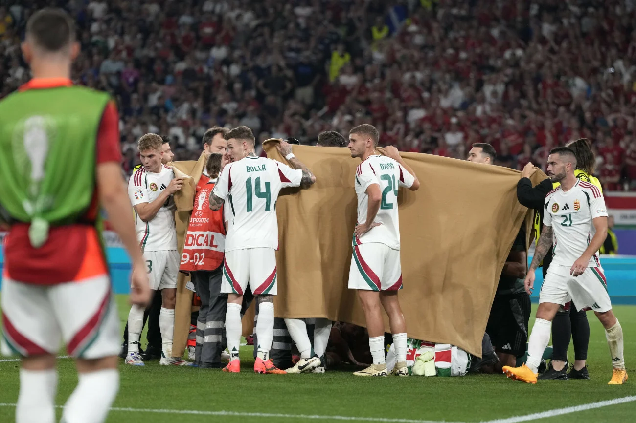 Węgierscy piłkarze pomagają zasłonić leżącego po zderzeniu z bramkarzem Barnabasa Vargę