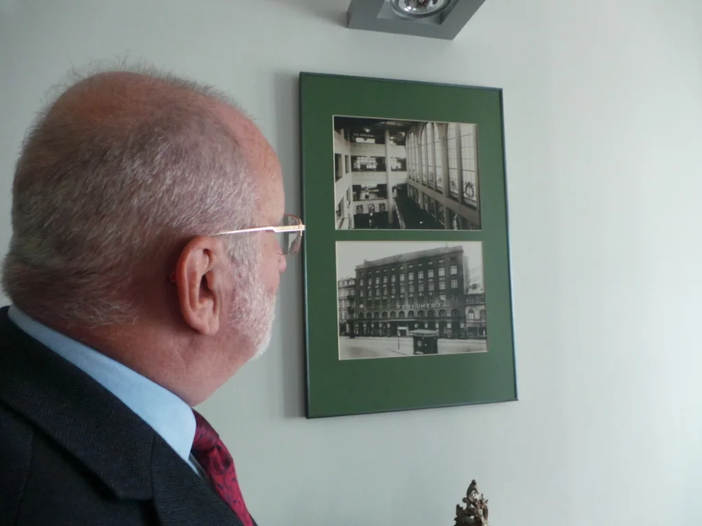 Jan Jabłkowski spoglądający na archiwalne zdjęcia kamienicy należącej do Braci Jabłkowskich
